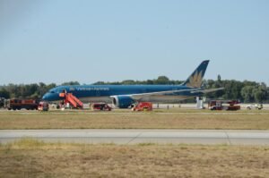 Vietnam Airlines Boeing 787 Suffers Tailstrike After Extended Takeoff Run At Munich SEO DES: The crew climbed to 9,000 feet and remained near Munich for two hours; Returned after tail-contact and low-tyre-pressure warnings, with damage SOCIAL: A Vietnam Airlines Boeing 787-9 flying from Munich to Hanoi took an unusually long takeoff roll on Runway 26L on August 15, 2026, before becoming airborne near the runway end. The aircraft reportedly travelled about 120 metres beyond the paved surface, with a tailstrike occurring during the late rotation. After takeoff, the crew climbed to around 9,000 feet and remained near Munich for about two hours before returning to the airport after warnings for tail contact and low tyre pressure. The aircraft sustained tail, landing-gear and tyre damage and could not taxi away after landing. The aircraft carried 271 passengers and 16 crew, all of whom were reported safe with no injuries. German authorities are leading the investigation, with Vietnamese investigators assisting, while the exact cause of the prolonged takeoff remains under investigation. Munich, Germany: A Vietnam Airlines Boeing 787-9 bound for Hanoi took an unusually long takeoff run from Munich Airport on August 15 before finally becoming airborne beyond the normal paved runway area, in an incident that resulted in runway damage, a tail strike and subsequent damage to the aircraft's landing gear. The aircraft later returned to Munich after remaining airborne for about two hours, with no injuries reported among the passengers or crew. The exact reason for the aircraft's prolonged acceleration and extremely late liftoff remains under investigation. The most significant part of the incident occurred during the takeoff roll. Video footage recorded from inside the cabin and from outside the airport shows the 787 accelerating along Runway 26L for an unusually long distance before rotation. Instead of lifting off with substantial runway remaining, the aircraft continued almost to the end of the approximately 4,000-metre runway. Reports based on flight-tracking data indicate that the aircraft reached the runway end area before becoming airborne, with reports putting the excursion beyond the paved surface at roughly 120 metres. The available video is particularly significant because it shows that the issue was not simply a conventional tailstrike during an otherwise normal rotation. The aircraft appears to remain on the ground for an unusually long period, with the runway threshold passing while the aircraft was still accelerating. It eventually rotated at the very end of the runway area, after which a large cloud of dust was visible beneath the rear of the aircraft. The reason for the unusually slow or prolonged takeoff has not been established. Online speculation has included possibilities such as an incorrect takeoff configuration, incorrect thrust or a problem affecting the aircraft's acceleration. However, none of those explanations has been confirmed by Vietnam Airlines or investigators and should not be presented as the cause. Vietnam Airlines has described the event as resulting from a technical issue and said the crew followed safety procedures. The airline has not publicly identified a specific technical failure responsible for the aircraft's unusually long takeoff roll. That distinction is important because the aircraft's subsequent warnings and damage do not, by themselves, establish what caused the initial lack of acceleration. Vietnam's aviation authorities have provided additional information on what happened after the aircraft became airborne. According to the latest reporting on the Civil Aviation Authority of Vietnam's information, warnings indicating tail contact and low tyre pressure were triggered shortly after takeoff. The authorities said the aircraft subsequently returned to Munich, while German authorities led the investigation with Vietnamese investigators assisting. After the aircraft finally lifted off, the crew did not immediately attempt to land. The Boeing 787 climbed to around 9,000 feet and remained in the Munich area for approximately two hours. During that period, the crew assessed the situation and reduced the aircraft's weight before returning to the airport. The tailstrike occurred as the aircraft became airborne after the exceptionally long takeoff run. The rear underside of the aircraft contacted the ground, producing the visible dust plume captured on video. A tailstrike can damage the aircraft's lower aft fuselage, pressure vessel, structural frames, systems, wiring and other components around the tail area. In this case, photographs and video circulating after the incident showed damage around the rear fuselage and the loss or damage of the Boeing 787's tailstrike protection component. The full extent of the structural damage, however, remains subject to technical inspection. The aircraft also sustained landing-gear and tyre damage. Reports indicate that several tyres were damaged or deflated, and footage following the return showed the aircraft unable to taxi away from the runway under its own power. The landing-gear damage also resulted in debris being left on the runway. The aircraft eventually landed back at Munich Airport, using the airport's other runway. Following the landing, the affected aircraft remained on the runway, forcing the closure of the runway and requiring airport authorities to clear debris and deal with the disabled aircraft. Traffic was subsequently handled through the other available runway, causing disruption at the German hub. There were no reported injuries among the passengers or crew. The aircraft was carrying passengers and crew on the Munich-Hanoi service; Vietnam Airlines has reported the total as 271 passengers and 16 crew members. All occupants were reported safe after the aircraft returned to Munich. The incident is now being examined by the relevant German authorities, with Vietnamese aviation investigators assisting. Investigators will need to establish why the Boeing 787 did not achieve the expected acceleration during the takeoff roll, why the aircraft reached the end of the runway area before becoming airborne and whether any technical, operational or performance-related factor contributed to the event.