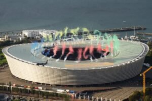 Airlink Formation Flypast Prompts Safety Review After Jets Pass 41 Feet Above Stadium SEO DES: Airlink said the flypast was planned and approved by SACAA, while the regulator is reviewing whether it complied with approved safety parameters SOCIAL: Two Airlink Embraer jets flew over Cape Town’s DHL Stadium on August 29, 2026, just before the Springboks-All Blacks Test. Flightradar24 estimated the lead aircraft passed only 41–46 feet above the stadium roof, raising safety concerns. Airlink said the flypast was carefully planned, rehearsed and approved by SACAA, with no passengers aboard and no reported injuries or aircraft damage. SACAA obtained the aircraft’s flight-data recordings and began reviewing whether the operation complied with approved safety parameters. SACAA has yet to issue its final findings. Meanwhile, Airlink withdrew its planned September 5 flypast at Johannesburg’s FNB Stadium, citing unfavourable weather, amid continuing scrutiny of the Cape Town operation. Cape Town, South Africa: Two Airlink Embraer jets flew as close as an estimated 41-46 feet (12.5-14 metres) above the roof of Cape Town’s DHL Stadium during a pre-match formation flypast on August 29, 2026, prompting a South African Civil Aviation Authority (SACAA) compliance review after footage of the manoeuvre went viral. The flypast took place shortly before the second Test between the Springboks and New Zealand’s All Blacks in the four-match Rugby’s Greatest Rivalry series. About 56,000 spectators were in the stadium as the two aircraft passed overhead before South Africa went on to defeat New Zealand 33-26. The aircraft involved were an Embraer E195, registration ZS-YDE, flying in a black All Blacks-themed livery, and an Embraer E190, registration ZS-YAE, carrying a green Springboks-themed livery. The E195 was the lead aircraft and was the one that came closest to the stadium roof based on flight-tracking calculations. Neither aircraft carried passengers. Airlink said each jet was operated by three senior captains serving as commander, co-pilot and safety/technical officer, with the crews having more than 75,000 combined flight hours. The aircraft flew at about 150 knots during the low-level formation pass. Airlink said the manoeuvre had been extensively planned and rehearsed and was conducted with guidance, approval and support from SACAA and Air Traffic Navigation Services. Flight-tracking service Flightradar24 later analysed ADS-B data from the operation. It recorded a lowest raw altitude of 50 feet at standard pressure. After correction for Cape Town’s local pressure setting of 1019 hPa, the aircraft were estimated to have been at about 205-210 feet above mean sea level. With DHL Stadium standing approximately 164 feet high, the estimated clearance above the roof was therefore about 41-46 feet. The low clearance became particularly striking in videos recorded from inside and around the stadium. The trailing aircraft was also seen passing through a cloud of pink dust or smoke generated by the pre-match pyrotechnic display. There has been no confirmed report of either aircraft striking the stadium, pyrotechnics or any other object, and no injuries or aircraft damage have been reported. Airlink defended the operation after the footage triggered criticism online. In its August 30, 2026 statement, the airline said the flight required “careful planning and rehearsal” because it involved low-altitude navigation at around 150 knots. It said SACAA and Air Traffic Navigation Services had provided guidance, approval and support to ensure a safe flyby. The airline also said flight data recorded by both aircraft confirmed that the operation was conducted within the altitude and speed limits approved and rehearsed with SACAA. The regulator subsequently began a compliance review. SACAA said Airlink had submitted three applications for flypasts linked to the rugby matches, with the first operation taking place at Ellis Park in Johannesburg on August 22, 2026 and the second at DHL Stadium on August 29, 2026. According to SACAA, the Cape Town operation had been formally approved under the regulatory provisions governing non-passenger or cargo-carrying flights under Part 91.06.32. The operator had also submitted supporting documentation, completed a simulator practice flight and conducted a safety briefing before the operation. The authority said the flypast was approved in accordance with the requirements for Special Air Events. However, after media and public discussion over the unusually low flight path, SACAA initiated compliance verification, engaged Airlink and obtained the aircraft’s Flight Data Recording downloads. SACAA said it is now analysing the data and has requested additional information from Airlink before reaching an informed position. The authority said a full report containing recommendations will be issued once the assessment is completed. “It is therefore critical that we interrogate this past weekend’s events to determine if there were any safety concerns which warrant a review,” SACAA said. The regulator also emphasised South Africa’s commercial aviation safety record, saying the country had maintained a zero fatal-accident record in commercial airline operations for more than four decades. SACAA said that record was one it intended to preserve as it continued to strengthen aviation safety standards. Airlink CEO de Villiers Engelbrecht later said the airline recognised the public interest generated by the flypast and the questions that followed, adding: “We never intended to become the news or upstage Rugby’s Greatest Rivalry.” Chris Martinus, president of the Aircraft Owners and Pilots Association South Africa, said the lead aircraft appeared to be manoeuvring over the stadium with very little room for error. He said that if something adverse occurred at such an altitude, the pilots would have few options. Australian aviation consultant and former military and commercial pilot Keith Tonkin also warned that turbulence or a bird strike could leave a jet with insufficient room to manoeuvre safely at that height. He said the broader concern was the precedent created by an operation that other operators might seek to replicate. The flypast was part of a long-standing South African rugby tradition. The practice gained particular prominence during the 1995 Rugby World Cup final, when a South African Airways Boeing 747 flew over Ellis Park before the Springboks faced the All Blacks. Airlink had planned to continue the tradition at the next Rugby’s Greatest Rivalry Test at Johannesburg’s FNB Stadium on September 5, 2026. However, the airline notified SACAA on September 1, 2026 that it was withdrawing its application for the third flypast. Airlink said unfavourable weather conditions meant the planned formation flight could not be safely conducted. SACAA confirmed the withdrawal but has not yet released a final finding on the Cape Town operation. The authority’s review will determine whether the two aircraft complied fully with the approved flight parameters and whether any additional safety measures or recommendations are required.